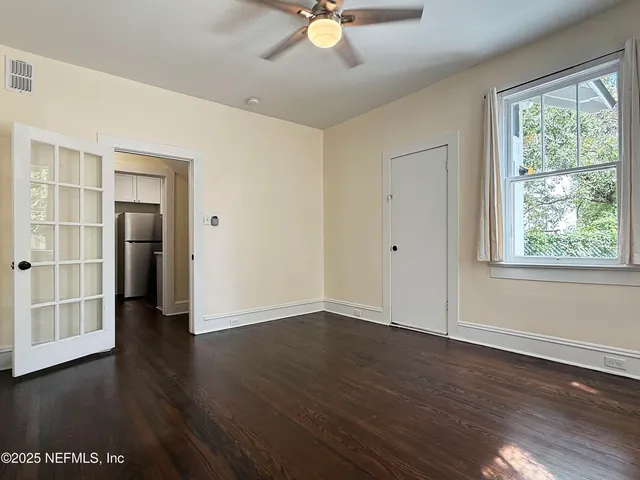 a view of an empty room with wooden floor and a window