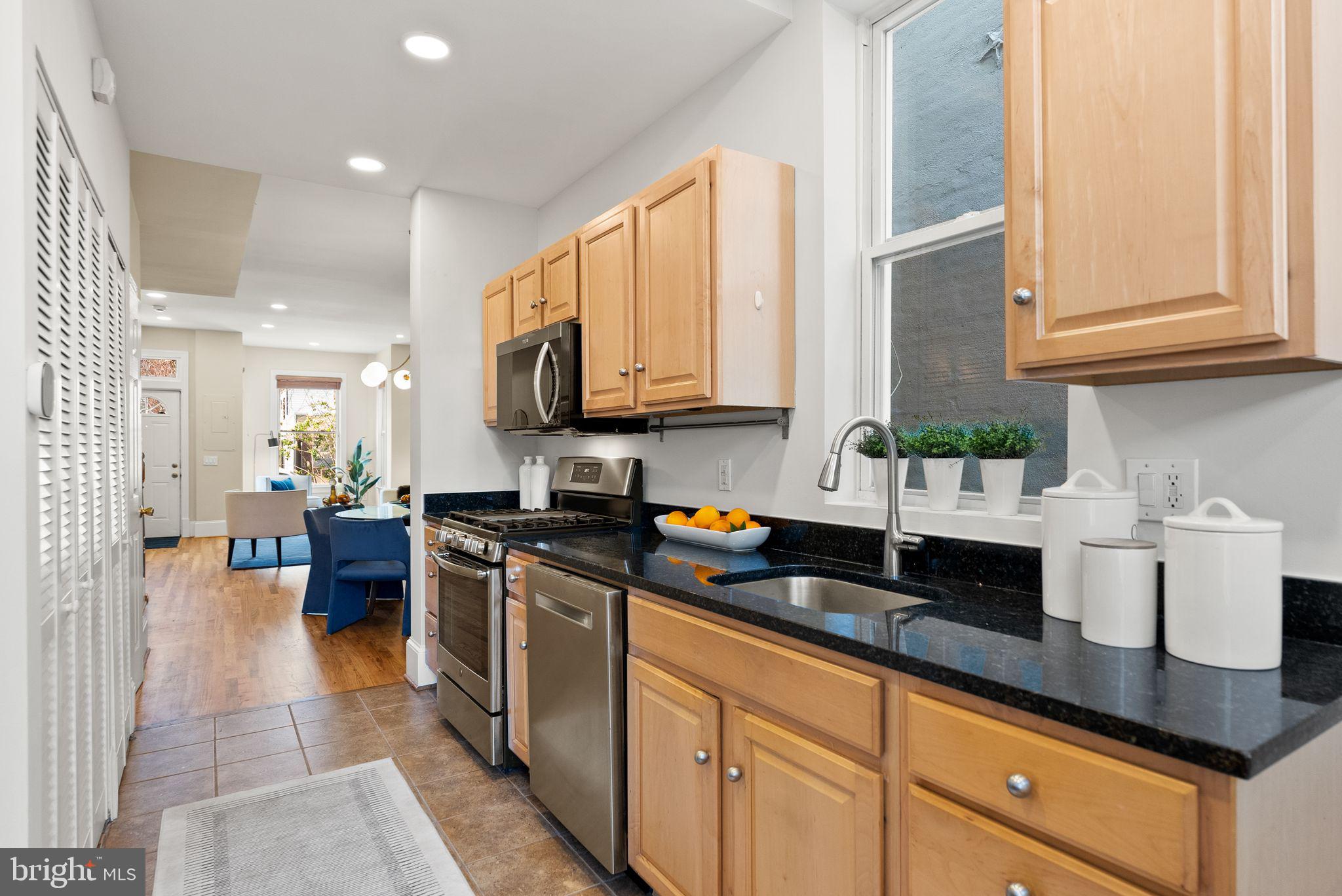 633 12th Street Northeast Washington, DC 20002 - Photo 14 of 44 a kitchen with stainless steel appliances granite countertop a coffee maker a sink a refrigerator and white cabinets with wooden floor
