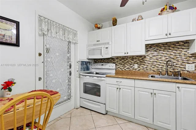 a kitchen with white cabinets and sink