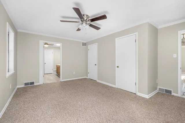 a view of a livingroom with a ceiling fan & windows