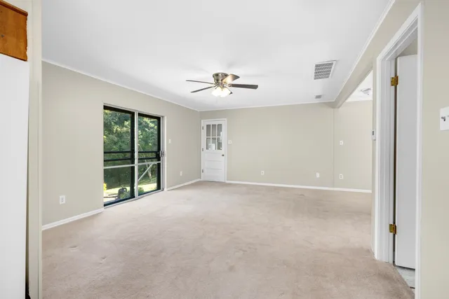 an empty room with windows and ceiling fan