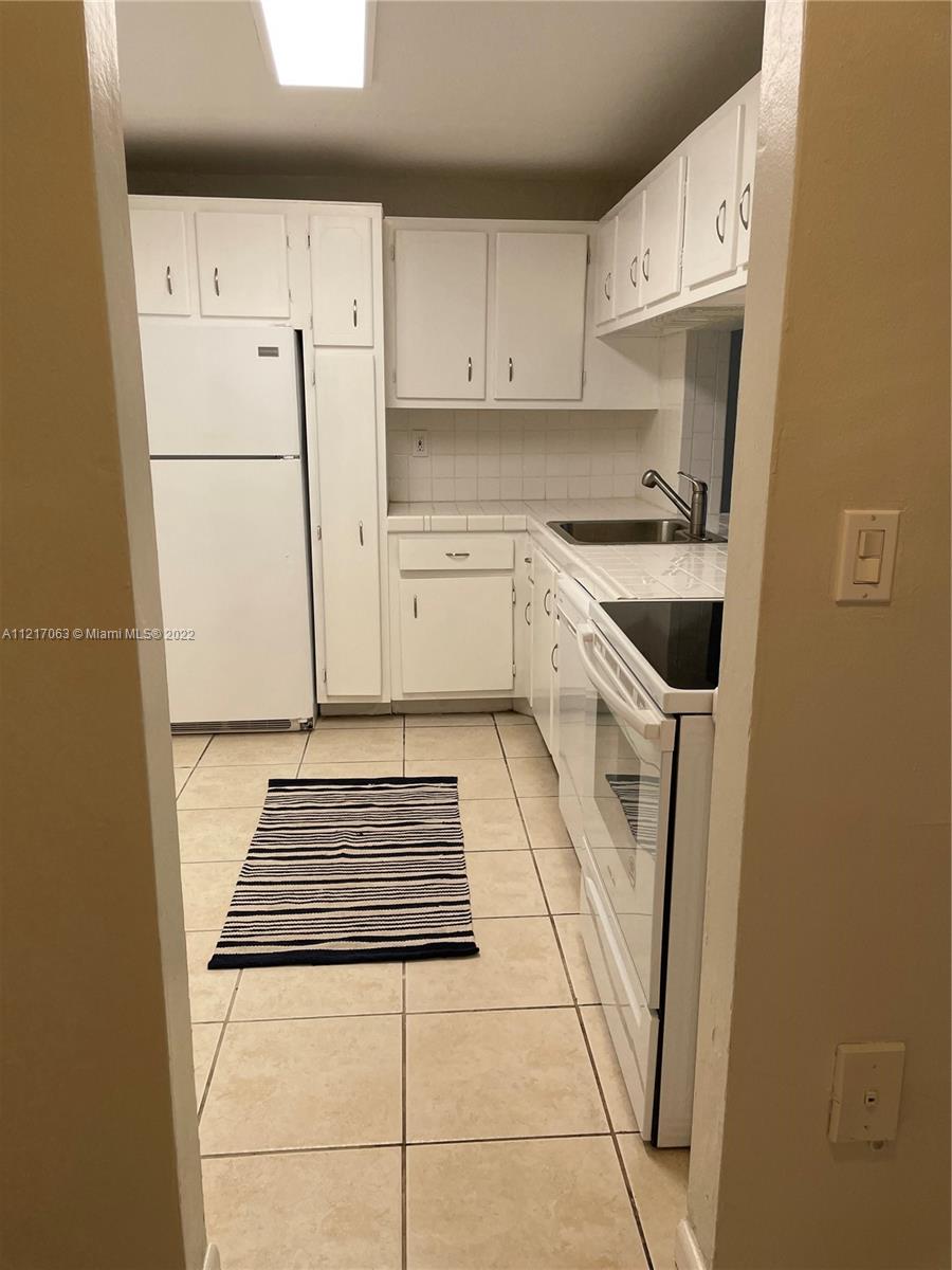 9611 Southwest 77th Avenue, Unit 108A Miami, FL 33156 - Photo 4 of 12 a kitchen with white cabinets and white appliances