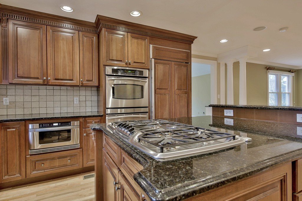 209 Main Street Boxford, MA 01921 - Photo 4 of 30 a kitchen with kitchen island granite countertop wooden cabinets and stainless steel appliances