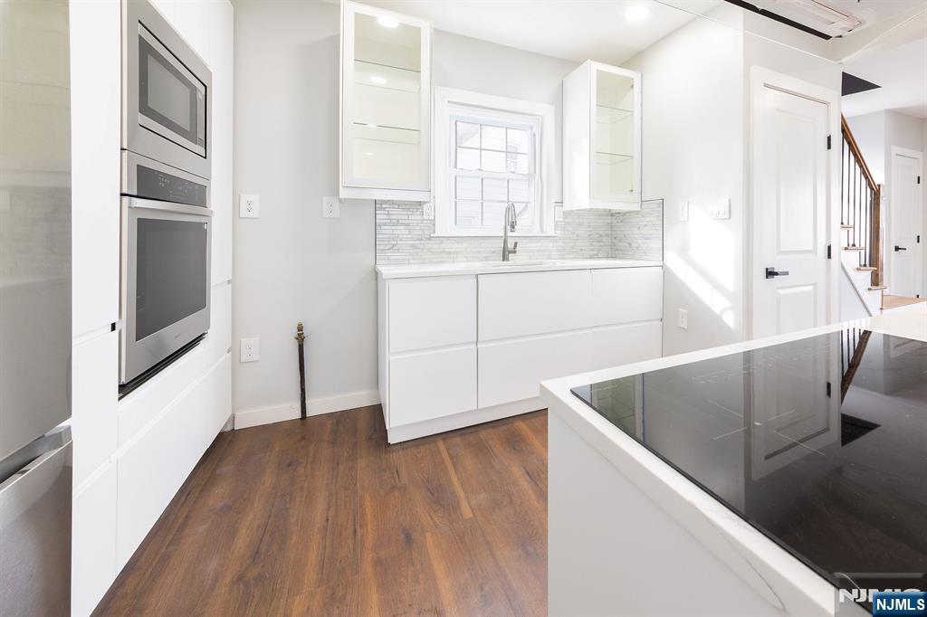 34 Kearny Street Lyndhurst, NJ 07071 - Photo 8 of 29 a kitchen with stainless steel appliances granite countertop a refrigerator a sink dishwasher and white cabinets with wooden floor