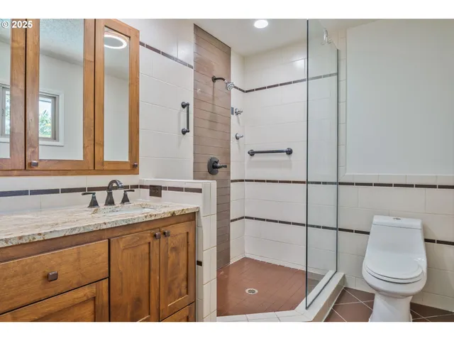 a bathroom with a granite countertop sink toilet and mirror
