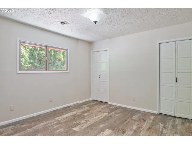 a view of an empty room with window and a ceiling fan
