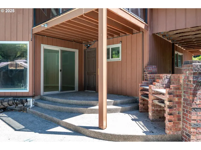 a view of a patio with table and chairs under an umbrella with a small yard