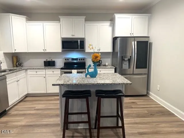 a kitchen with granite countertop a stove a sink dishwasher a refrigerator with wooden floor and cabinets