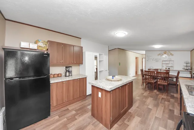 a kitchen with stainless steel appliances granite countertop a refrigerator a stove a sink a dining table and chairs