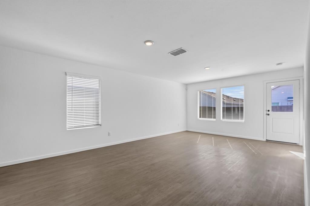 Spacious room featuring wood-finish flooring, recessed lighting, and multiple windows with blinds