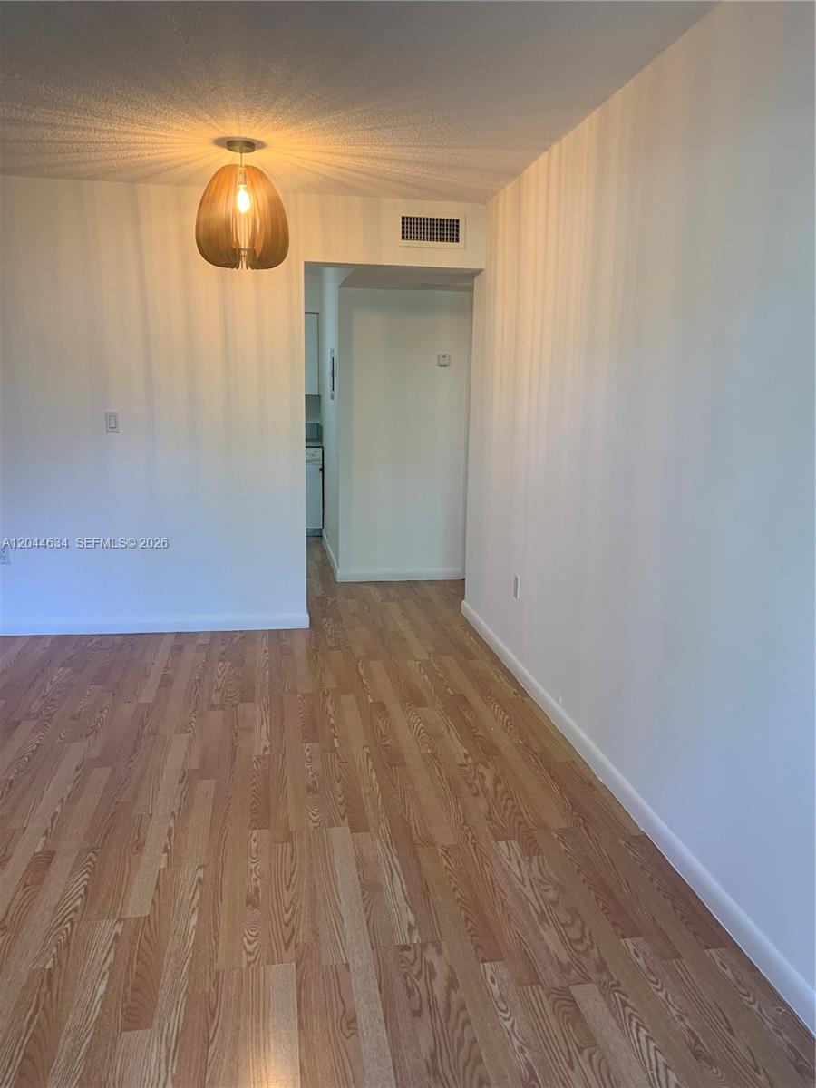 2460 Southwest 18th Avenue, Unit 1205 Miami, FL 33133 - Photo 3 of 21 an empty room with wooden floor and mirror