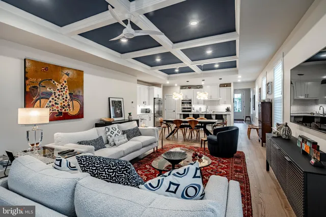 a living room with furniture kitchen view and a large window