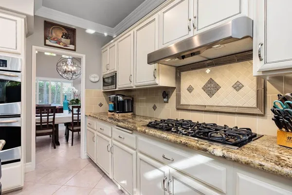 a kitchen with stainless steel appliances granite countertop table chairs and a wooden cabinets