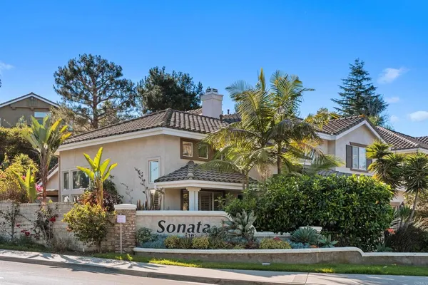 a front view of a house with a yard and palm trees
