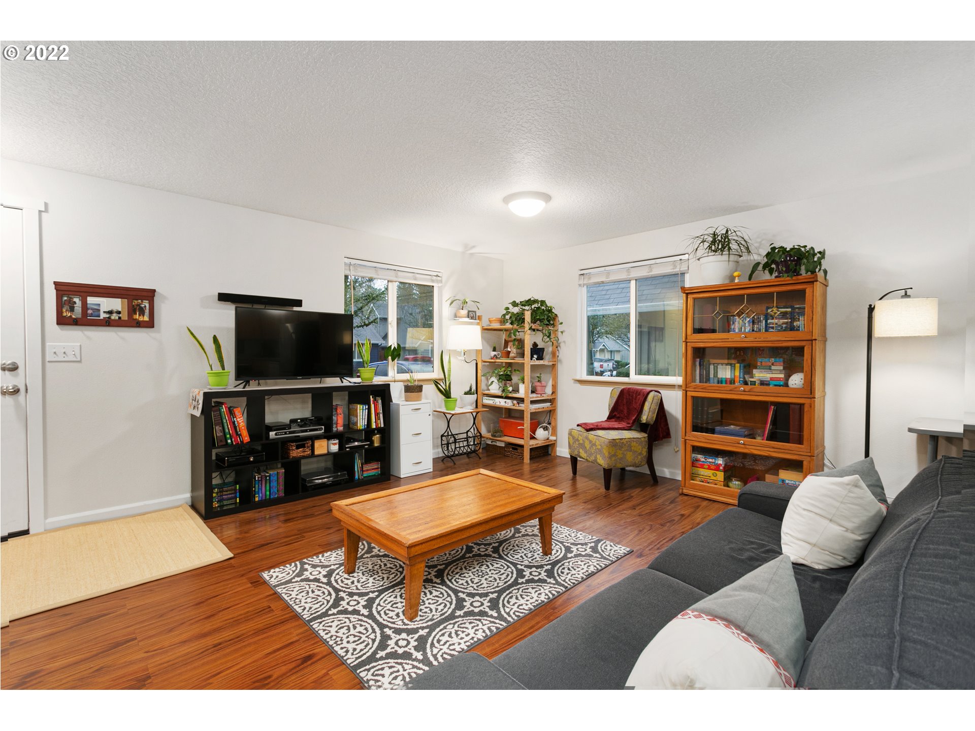 601 West 1st Street, Unit 18 Newberg, OR 97132 - Photo 5 of 21 a living room with furniture a bookshelf and a flat screen tv