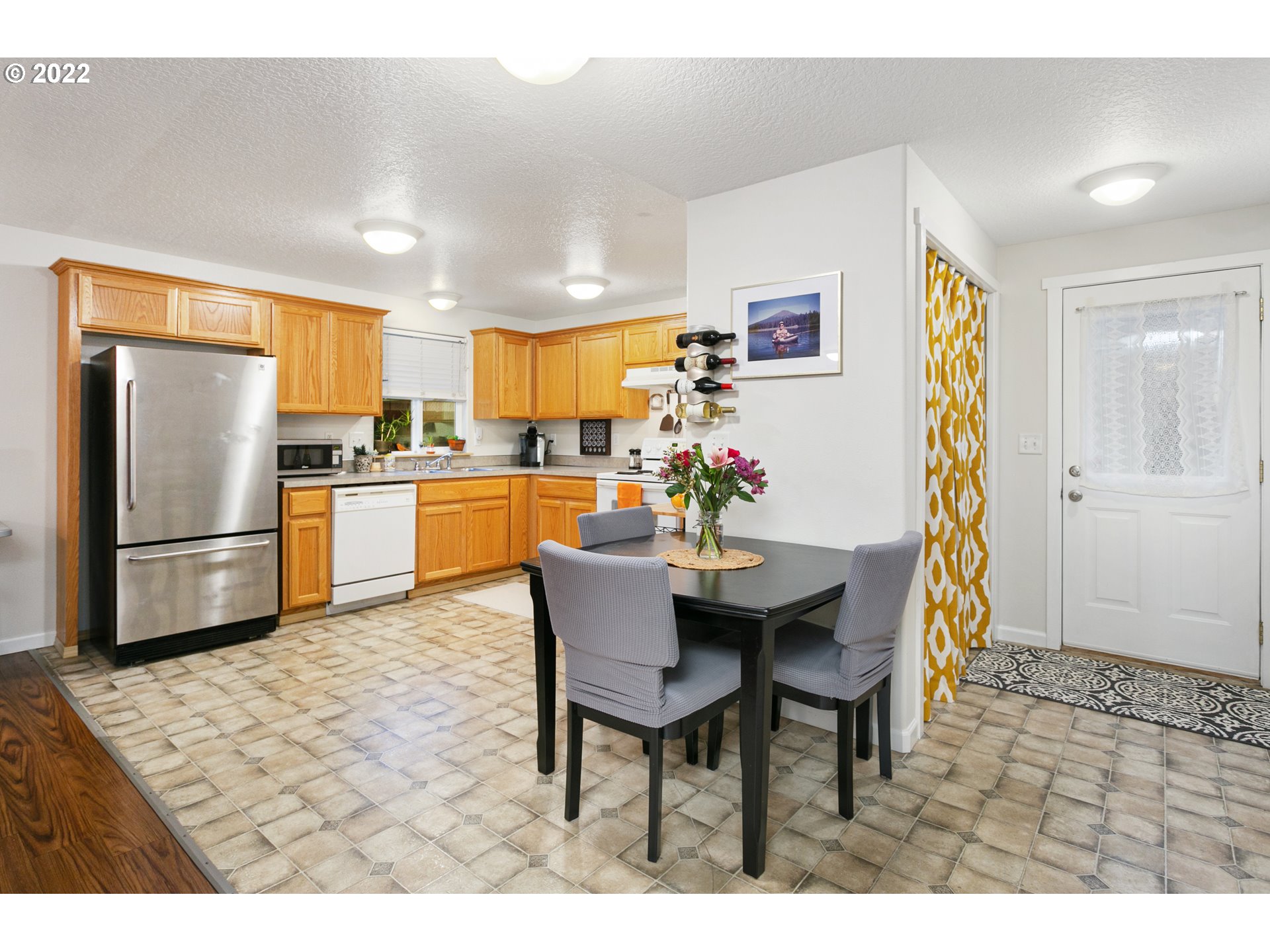 601 West 1st Street, Unit 18 Newberg, OR 97132 - Photo 9 of 21 a kitchen with stainless steel appliances kitchen island granite countertop a refrigerator a stove a sink dishwasher with a dining table and chairs