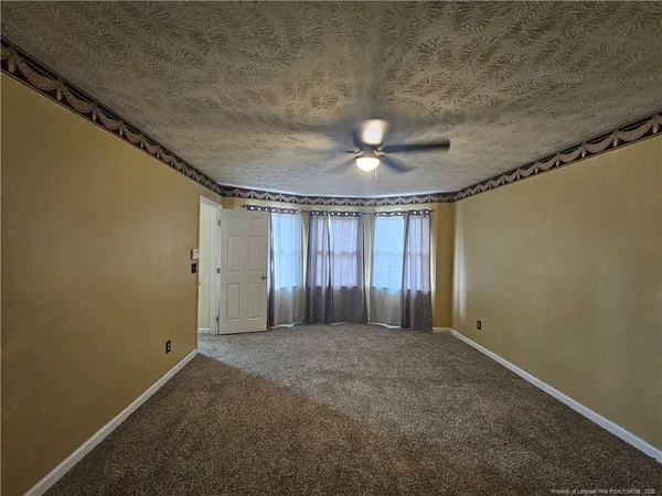 an empty room with a chandelier fan and windows