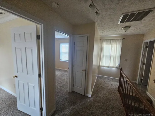 an empty room with chandelier fan and windows