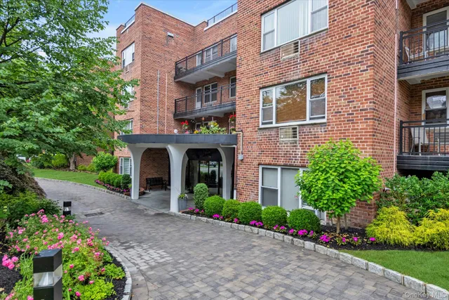 a front view of multi story residential apartment building with yard and flowers