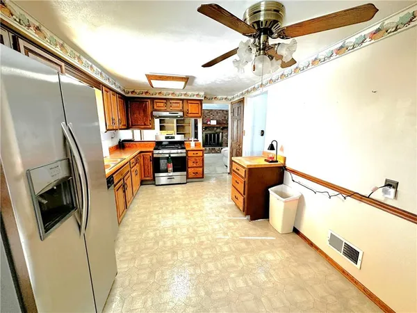 a living room with stainless steel appliances furniture and a kitchen view