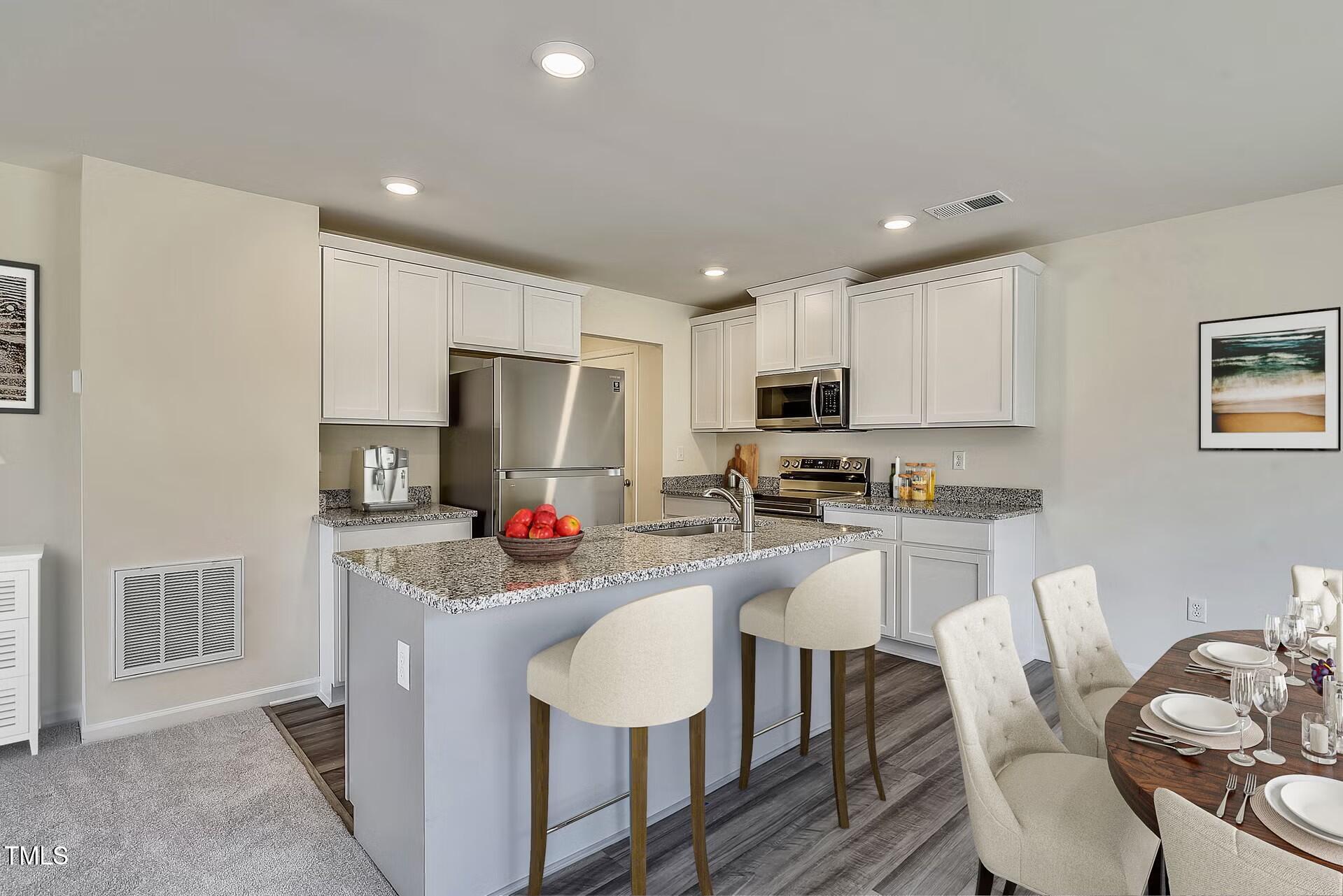 2700 Barrington Drive Raleigh, NC 27610 - Photo 19 of 27 a kitchen with stainless steel appliances granite countertop a refrigerator a stove top oven a sink dishwasher a dining table and chairs with wooden floor
