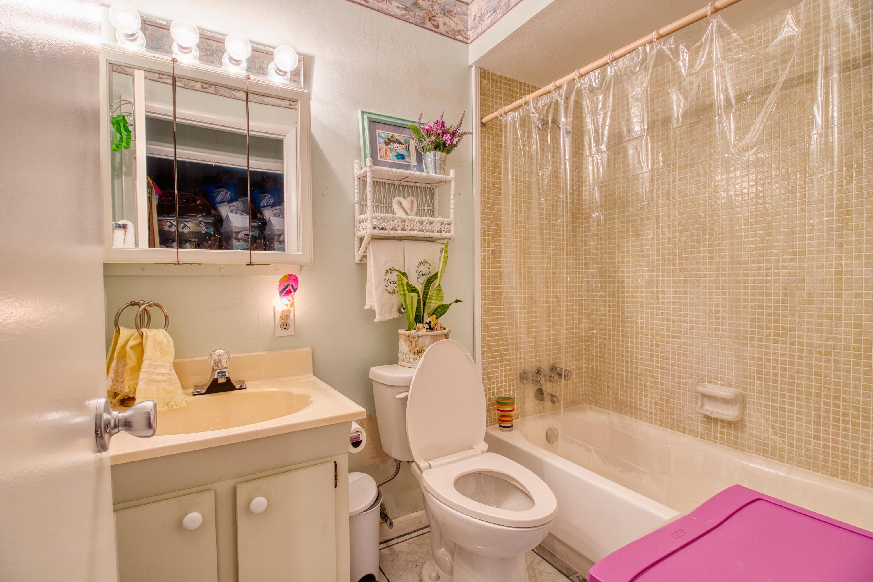1911 Southwest Palm City Road, Unit J Stuart, FL 34994 - Photo 10 of 42 a bathroom with a sink a toilet and shower curtain