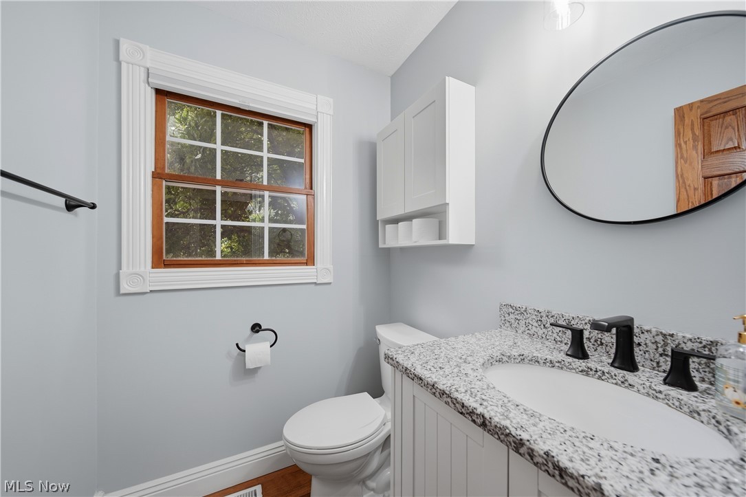 4764 Young Road Stow, OH 44224 - Photo 18 of 41 Bathroom featuring a granite countertop with an undermount sink, matte black faucet, and a contemporary round mirror