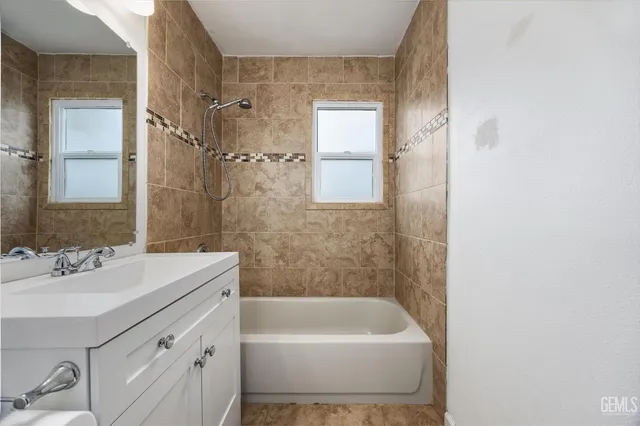 a bathroom with a sink a mirror a bathtub and shower