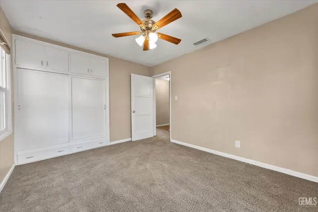 an empty room with closet and a ceiling fan