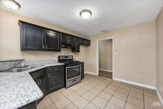 a kitchen with granite countertop a sink stove and cabinets