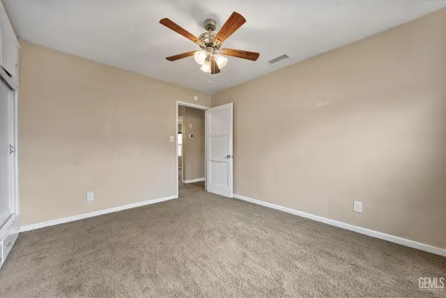 an empty room with closet and fan