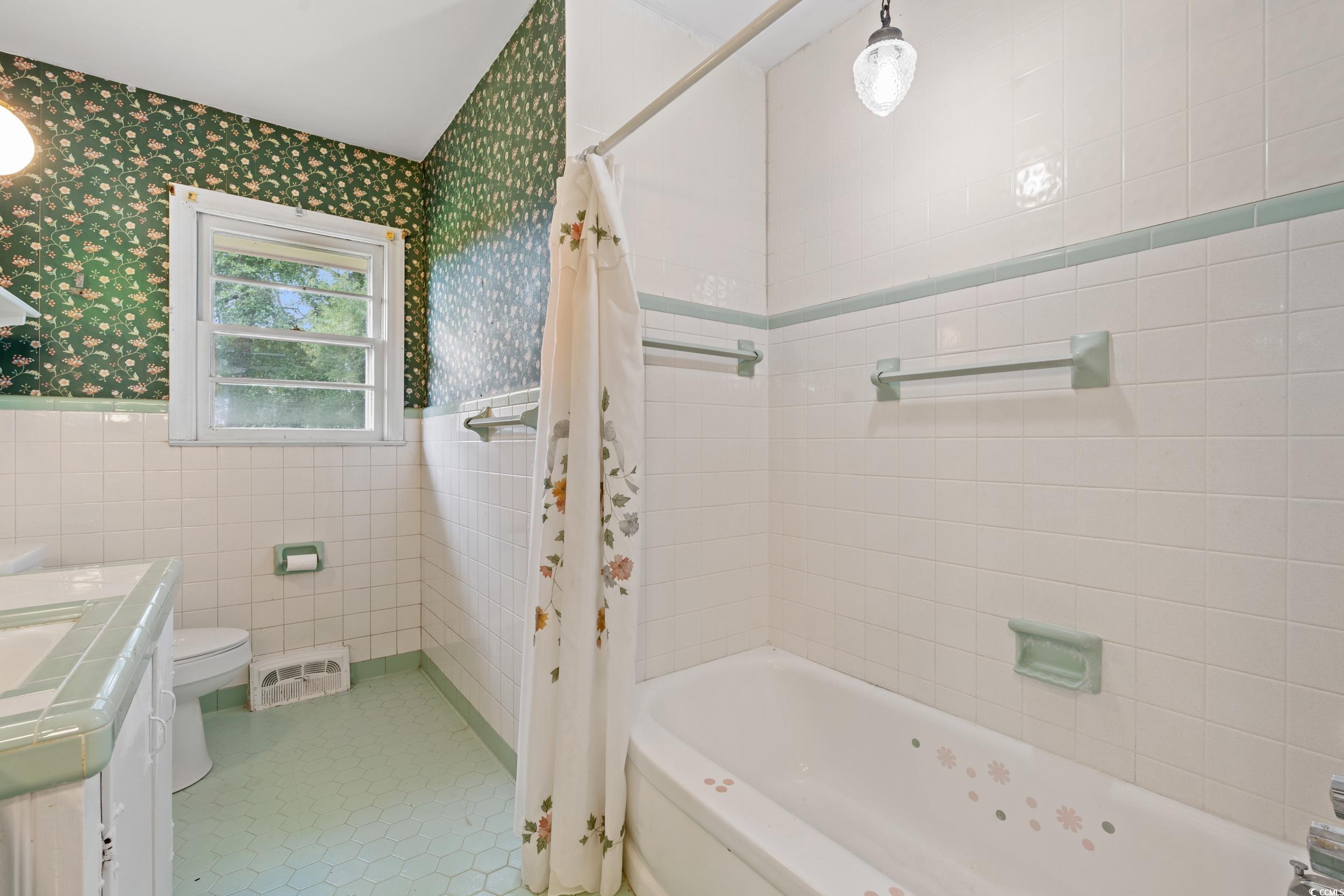 4155 Pinewood Drive Mullins, SC 29574 - Photo 16 of 33 Bathroom with tile walls, wainscoting, wallpapered walls, vanity, and shower / bath combination with curtain