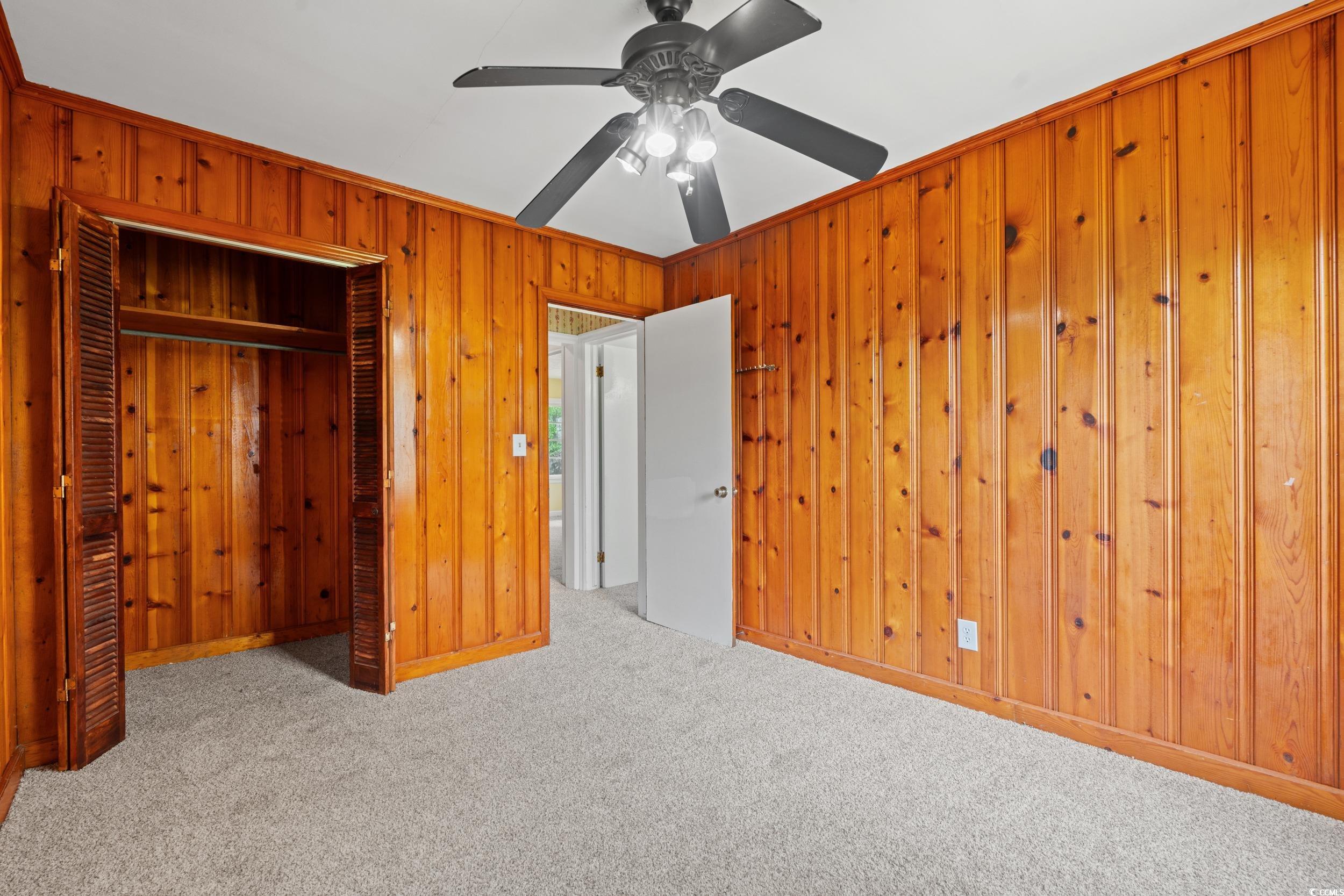 4155 Pinewood Drive Mullins, SC 29574 - Photo 17 of 33 Unfurnished bedroom with wooden walls, carpet flooring, a closet, and a ceiling fan