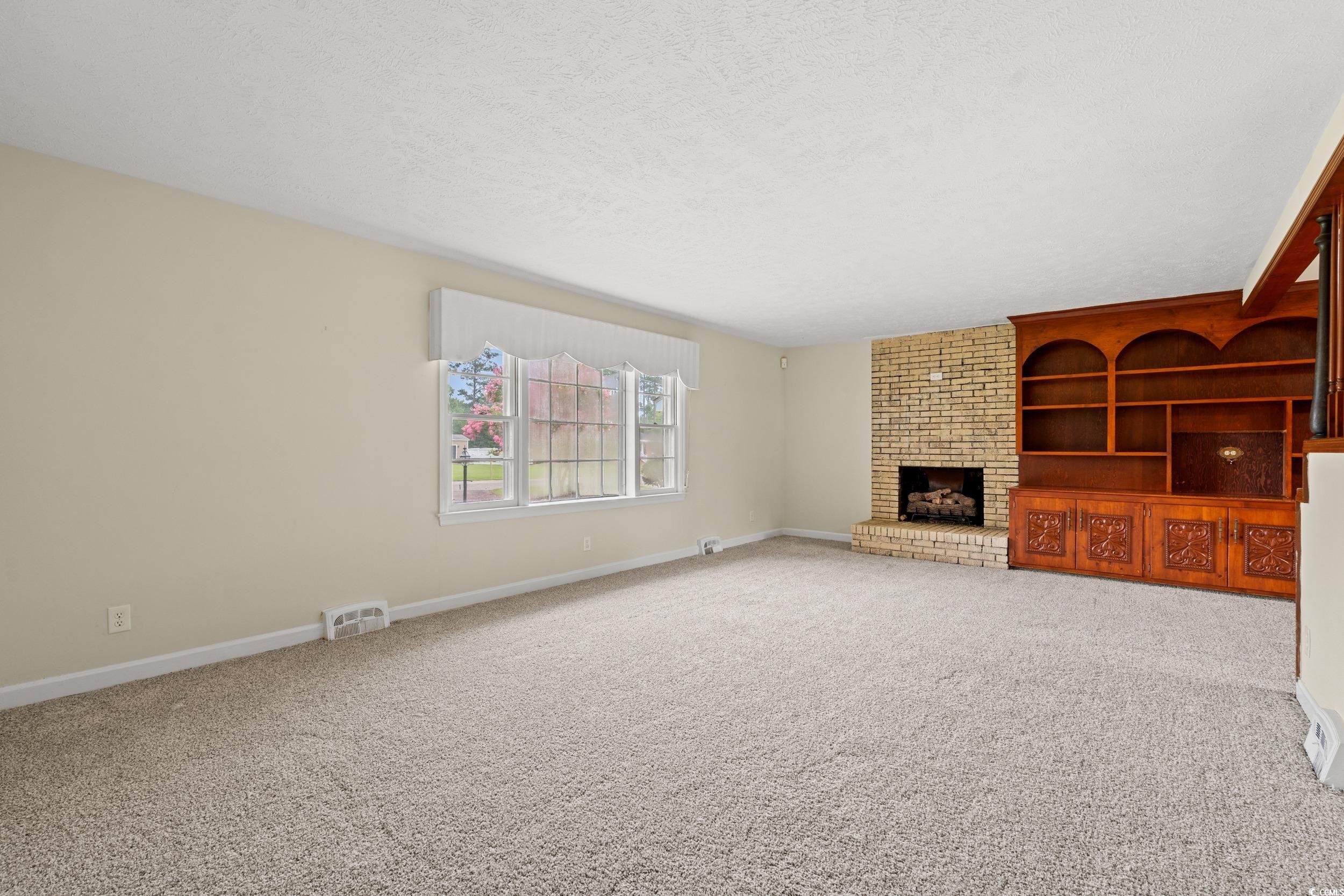 4155 Pinewood Drive Mullins, SC 29574 - Photo 3 of 33 Unfurnished living room featuring carpet flooring, a fireplace, and a textured ceiling