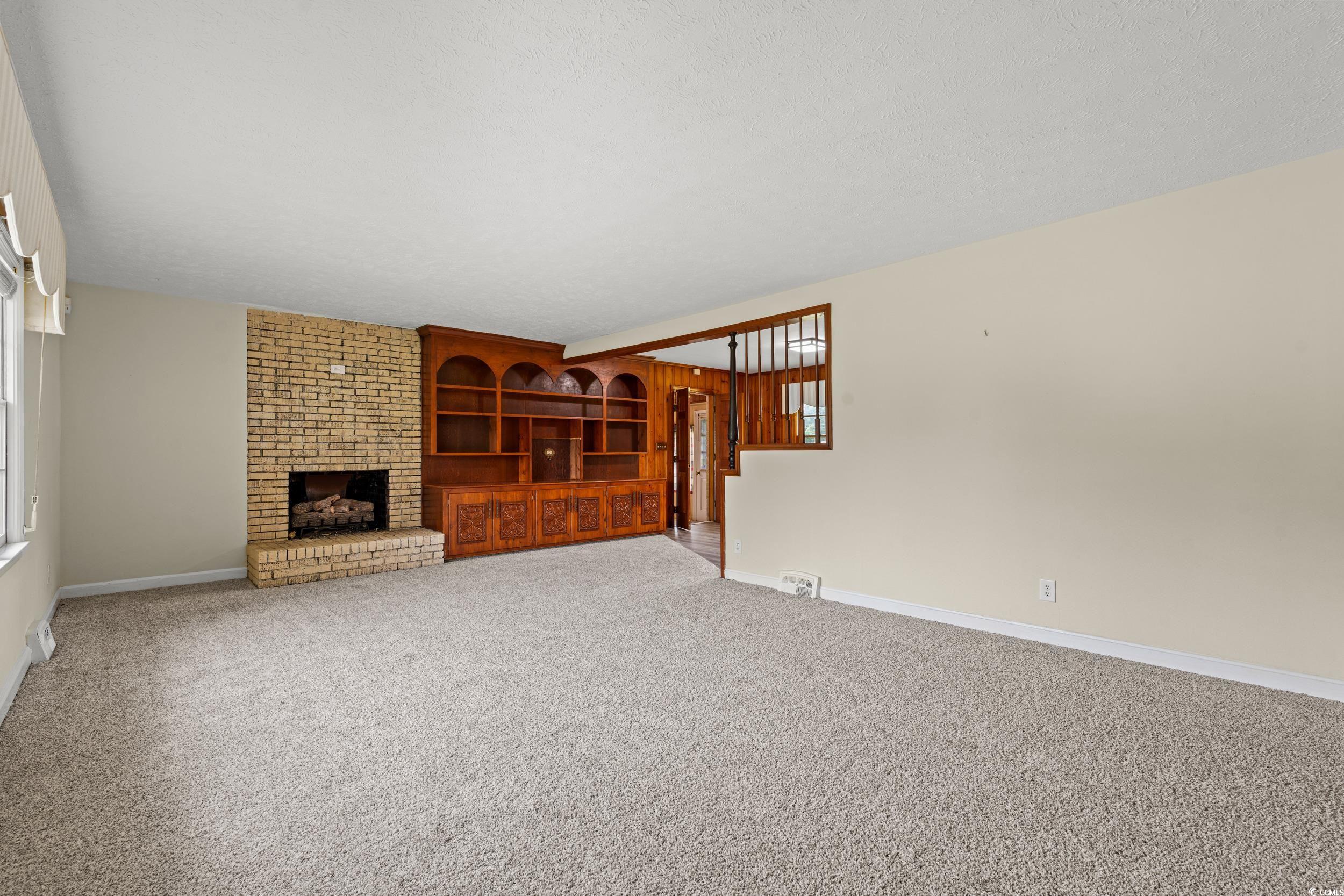 4155 Pinewood Drive Mullins, SC 29574 - Photo 4 of 33 Unfurnished living room featuring carpet, a fireplace, and a textured ceiling