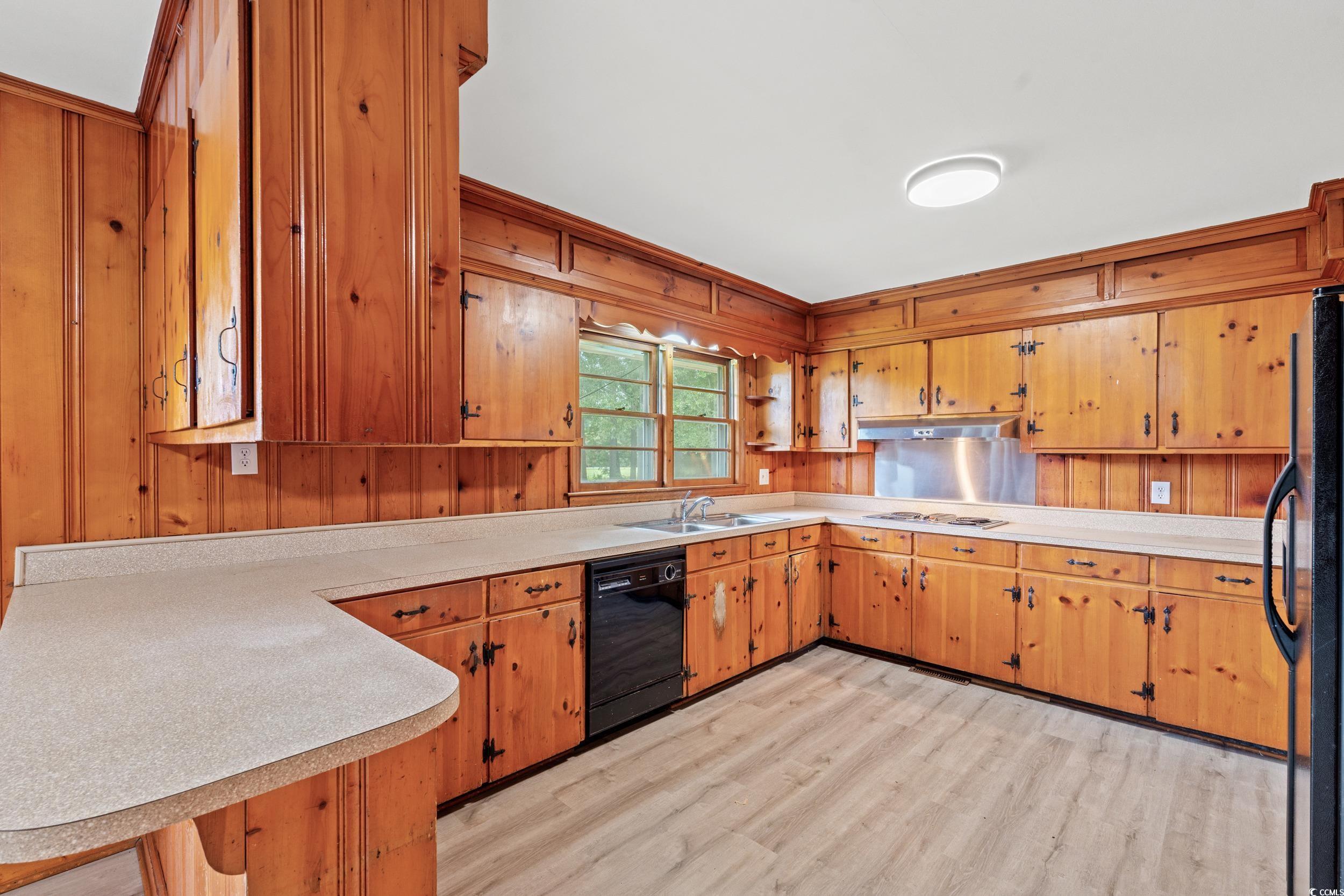 4155 Pinewood Drive Mullins, SC 29574 - Photo 6 of 33 Kitchen featuring light countertops, light wood-style flooring, black appliances, a peninsula, and wooden walls