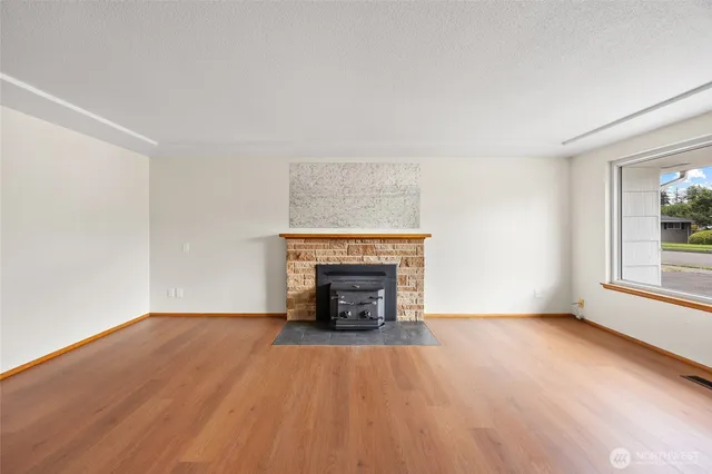 an empty room with wooden floor fireplace and windows