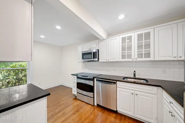 a kitchen with stainless steel appliances granite countertop a sink a stove a microwave and wooden floors