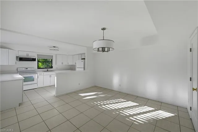 a kitchen with white cabinets and window