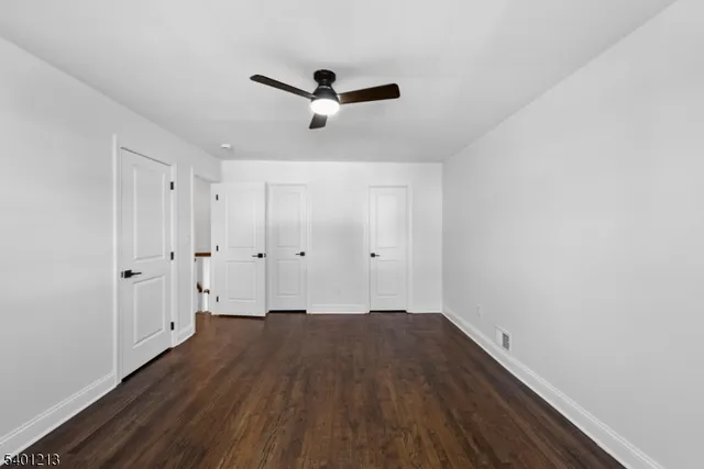 an empty room with wooden floor chandelier and windows