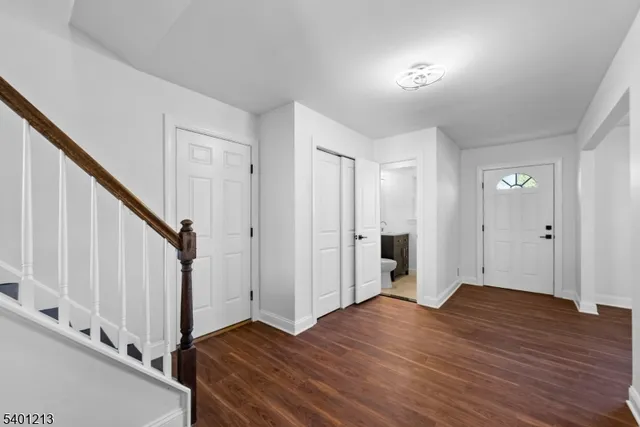 a view of an empty room with wooden floor and stairs