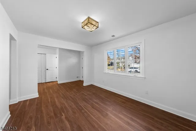 a view of an empty room with window and wooden floor