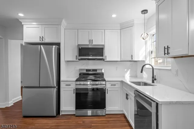 a kitchen with stainless steel appliances a stove a sink a refrigerator and a microwave