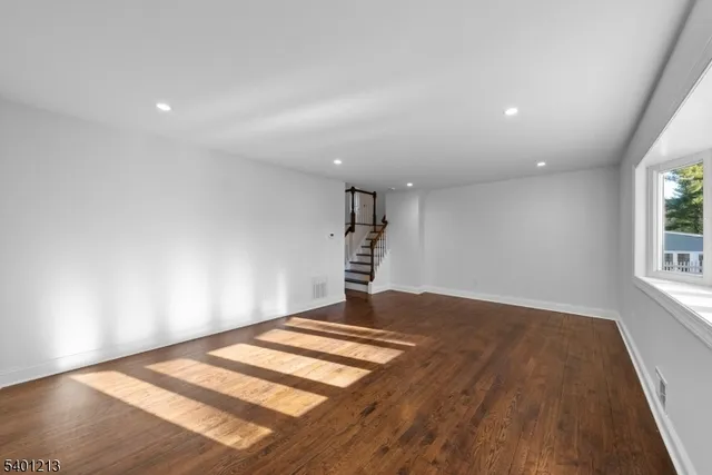 a view of a big room with wooden floor and windows