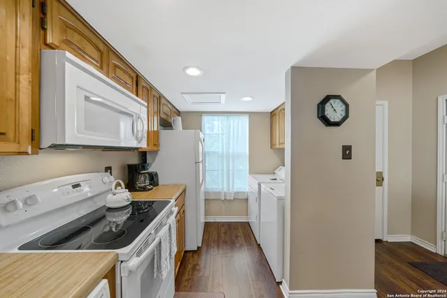 a kitchen with a refrigerator a stove and wooden floor
