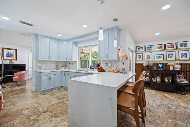 a living room with stainless steel appliances kitchen island granite countertop a table chairs and a refrigerator