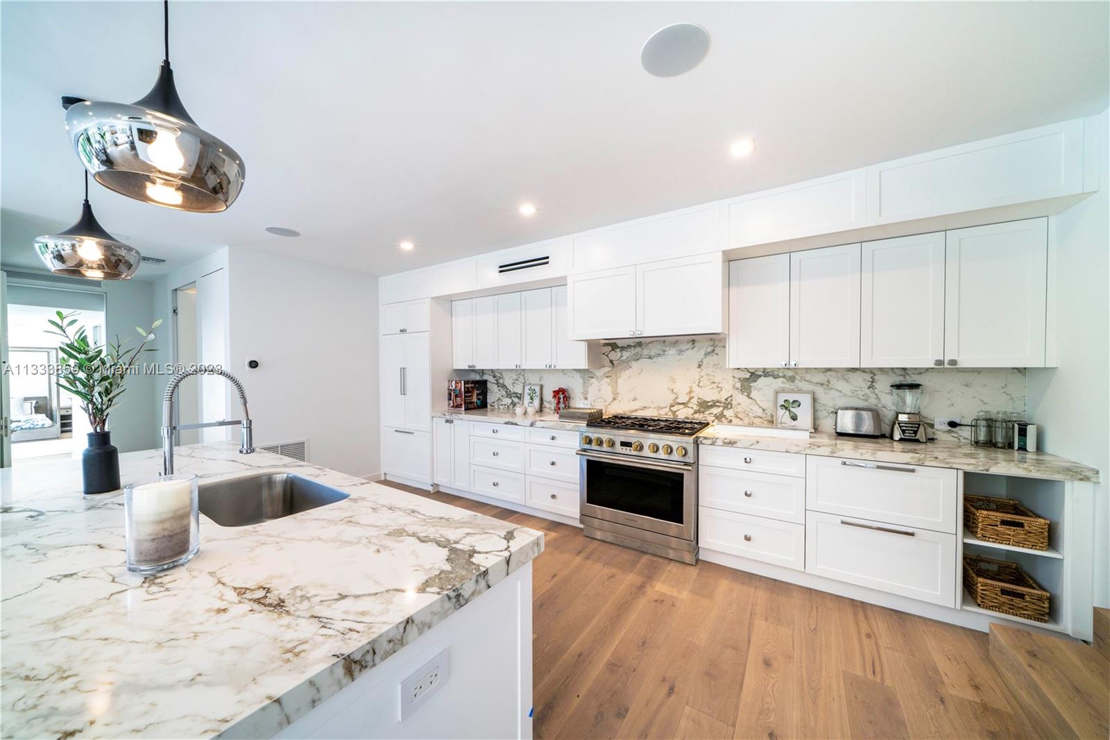 5334 Pine Tree Drive Miami Beach, FL 33140 - Photo 7 of 42 a kitchen with a stove a sink a dining table and chairs with wooden floor