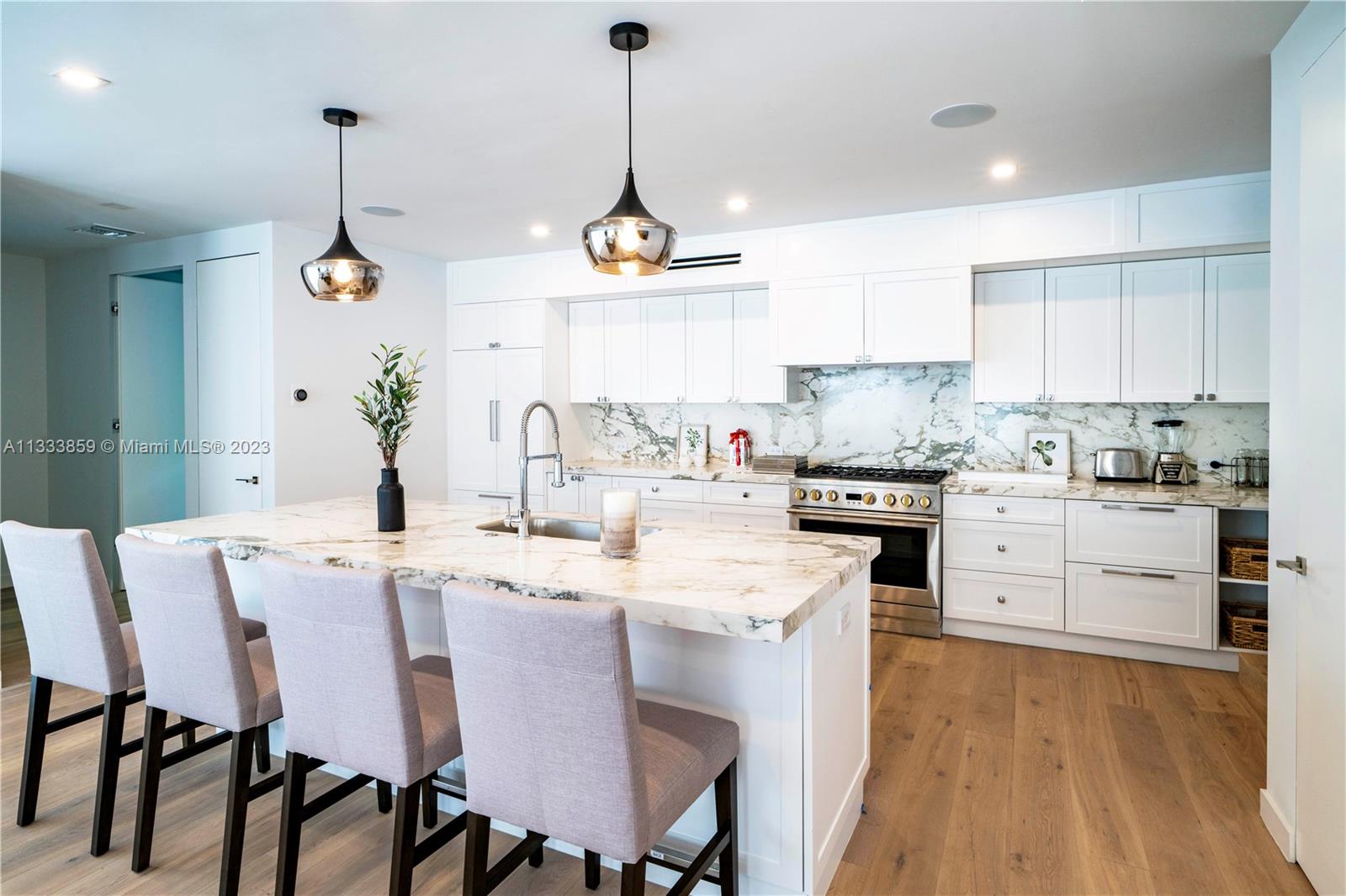 5334 Pine Tree Drive Miami Beach, FL 33140 - Photo 8 of 42 a kitchen with a dining table chairs stainless steel appliances and cabinets