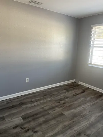 an empty room with wooden floor and window