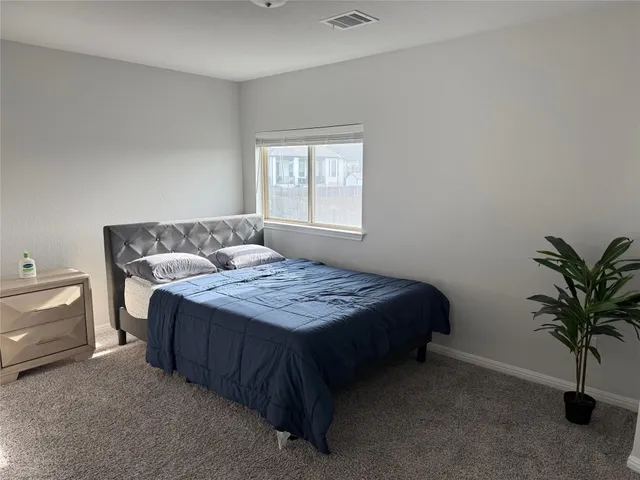 a bedroom with a bed and a potted plant on the dresser